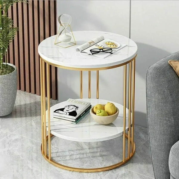 Modern 2-tier gold side table with white faux marble top, styled in light-filled lounge with sofa and indoor plants