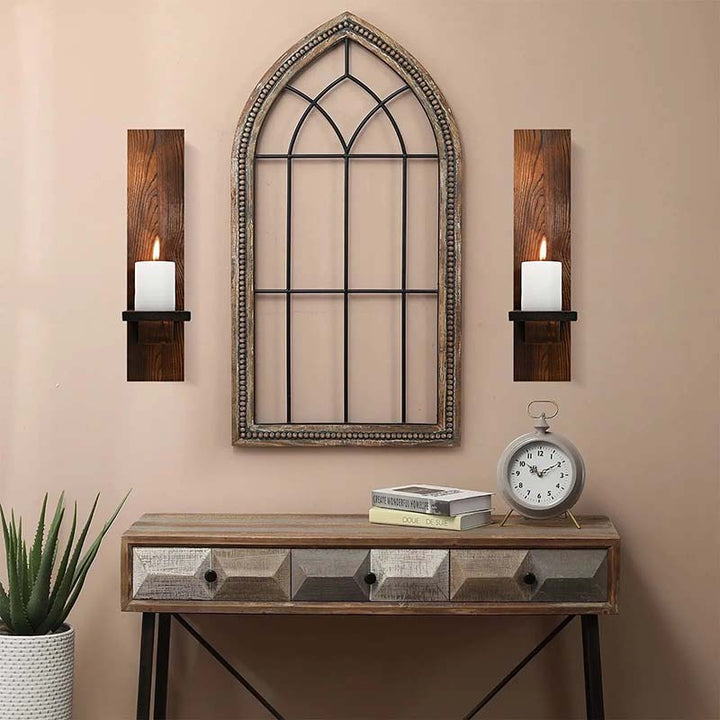 Decorative wall mirror with wooden sconces and a clock on a console table against a beige wall.