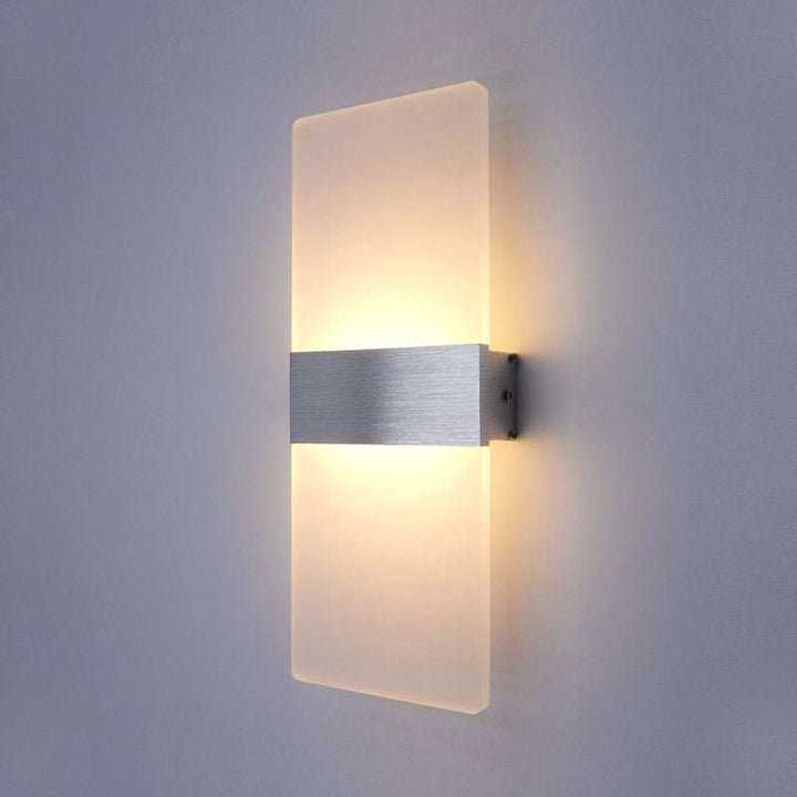 Modern LED wall lamp with frosted glass panel and brushed aluminium center strip mounted on wall, glowing with warm light.