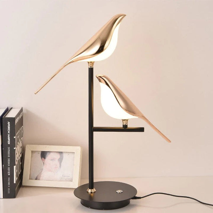 Dual golden bird LED lamp with soft warm glow on nightstand beside decor.