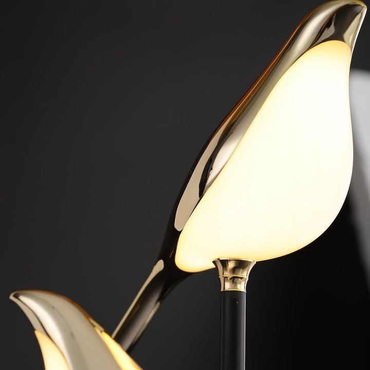 Close-up of illuminated golden bird LED lamp showing glossy metal detailing.