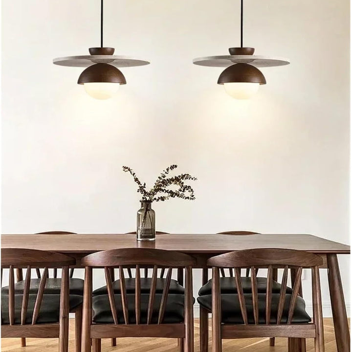 Dining room with wooden table and chairs, and pendant lights on a neutral wall.
