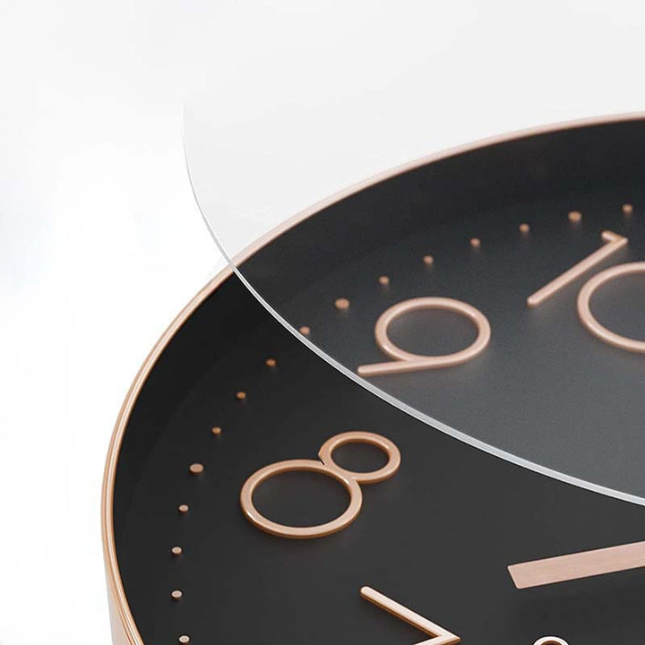 Close-up of a clock with black face and rose gold numbers and hands on a white background