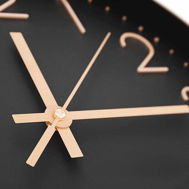 Close-up of a clock with rose gold hands and numbers on a black background