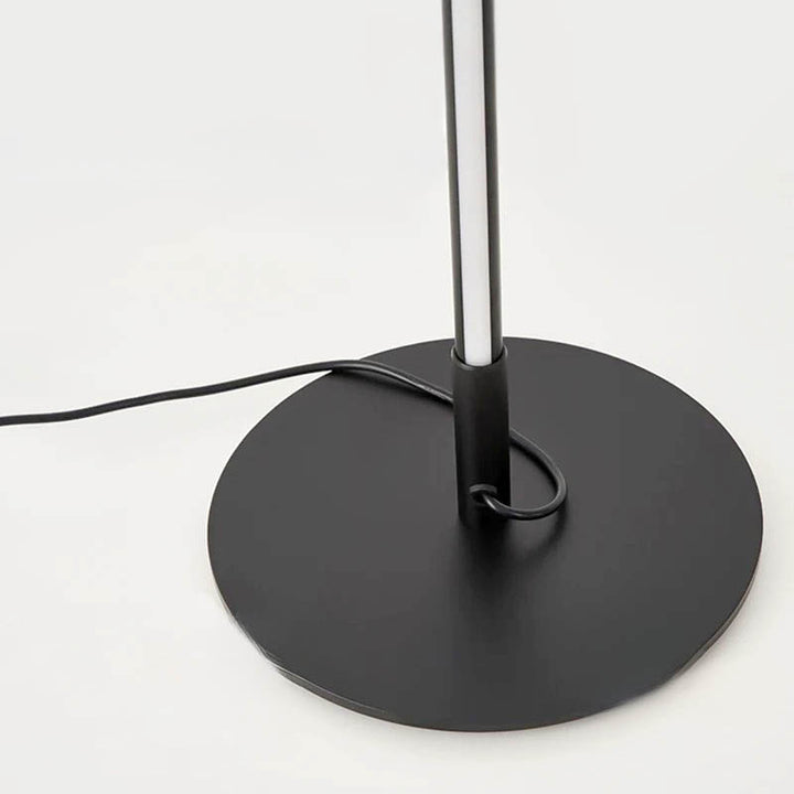 Close-up of matte black circular base and pole connection for slimline LED floor lamp.
