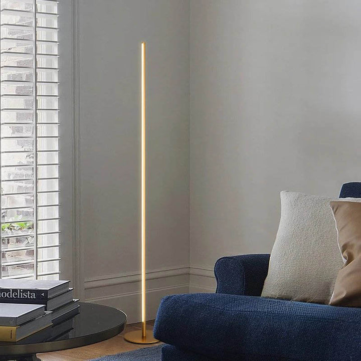 Warm white dimmable LED floor lamp in gold, styled in a Scandinavian living room next to a navy armchair