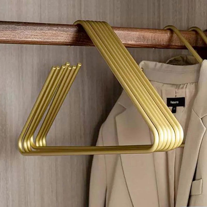 Set of golden triangle aluminium hangers on wooden rod, sleek and durable closet organisers for coats or shirts.