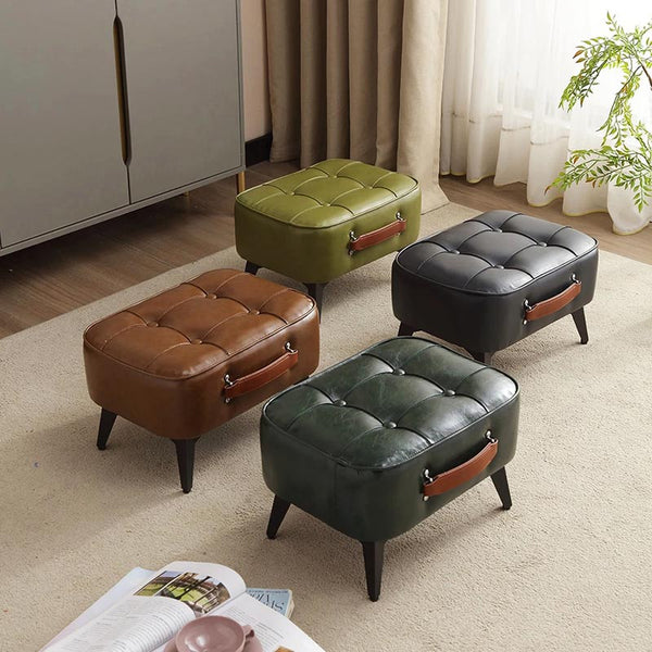 Group shot of four ottomans in green, brown, black and olive faux leather with handles on a beige rug in modern UK interior