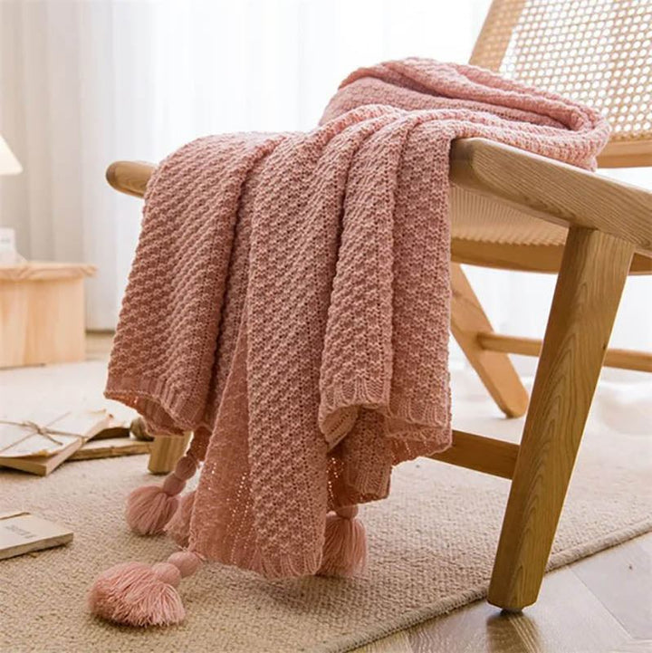 Neutral-toned Nordic knitted throw blankets with tassels, soft cotton blend, folded on chair, ideal for sofa or bed. Pink2