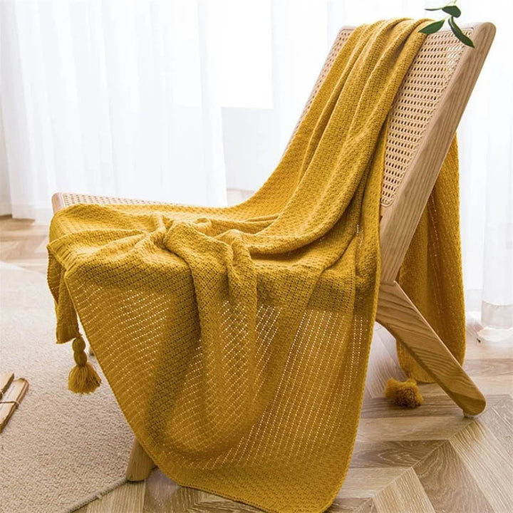 Neutral-toned Nordic knitted throw blankets with tassels, soft cotton blend, folded on chair, ideal for sofa or bed. Yellow