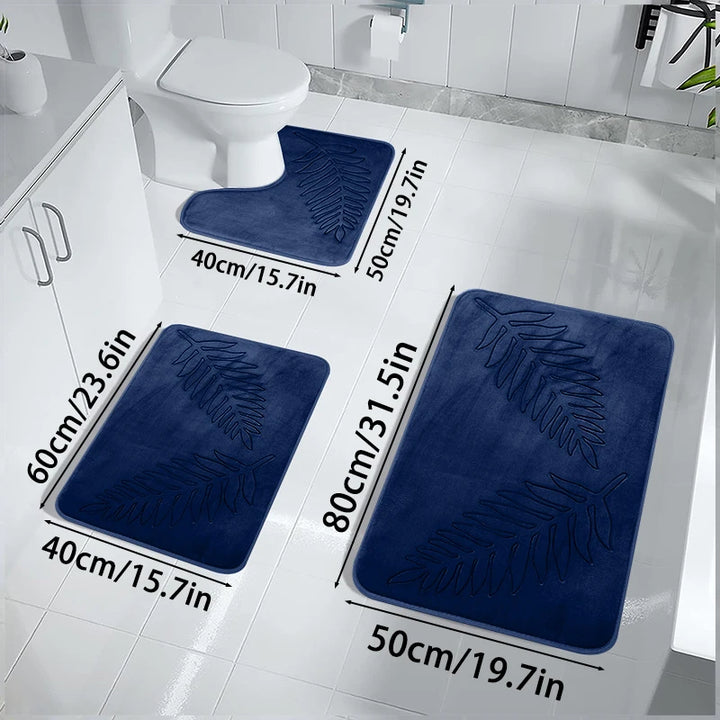 Set of three blue bath mats with measurements on a white bathroom floor.