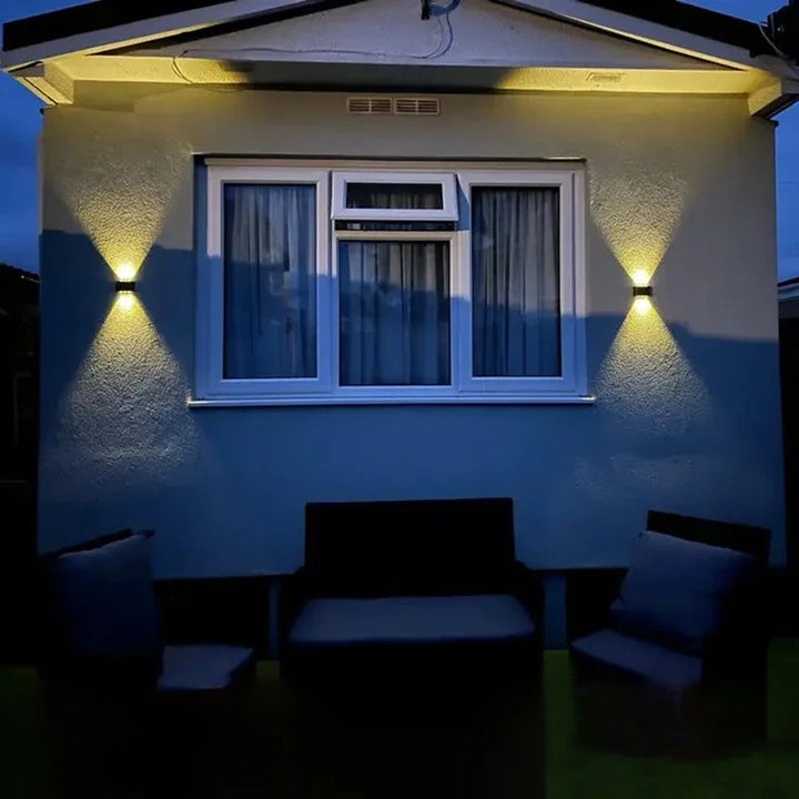 Outdoor LED solar wall light casting elegant V-shaped light on white exterior wall—ideal for UK fences and UK. walkways.
