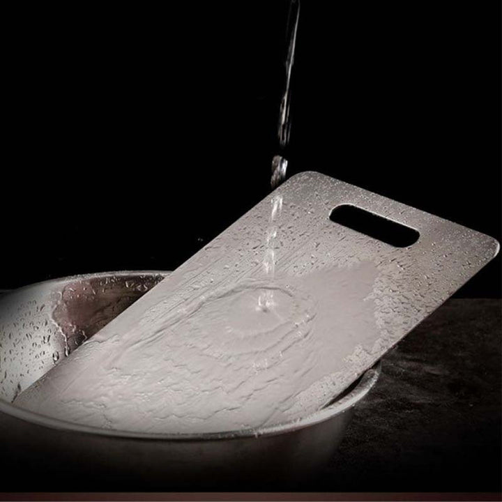 Stainless-Steel Cutting Board being rinsed with water in a sink against a black background