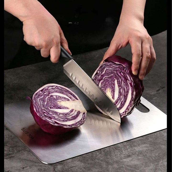 Person cutting a red cabbage on Stainless-Steel Chopping Board with a knife.