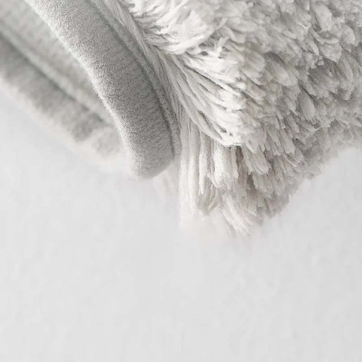 Close-up of a textured gray rug on a light gray background