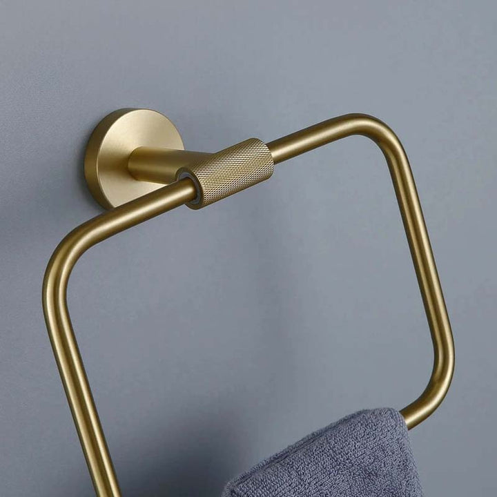 Gold towel holder with a gray towel on a gray wall
