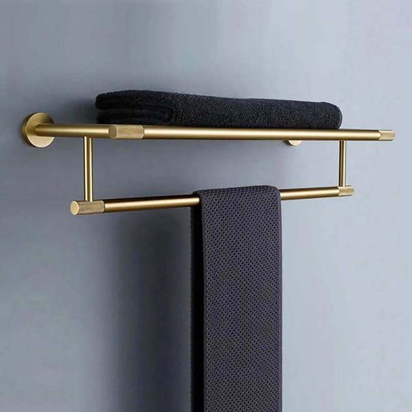 Gold towel rack with black towels on a gray wall