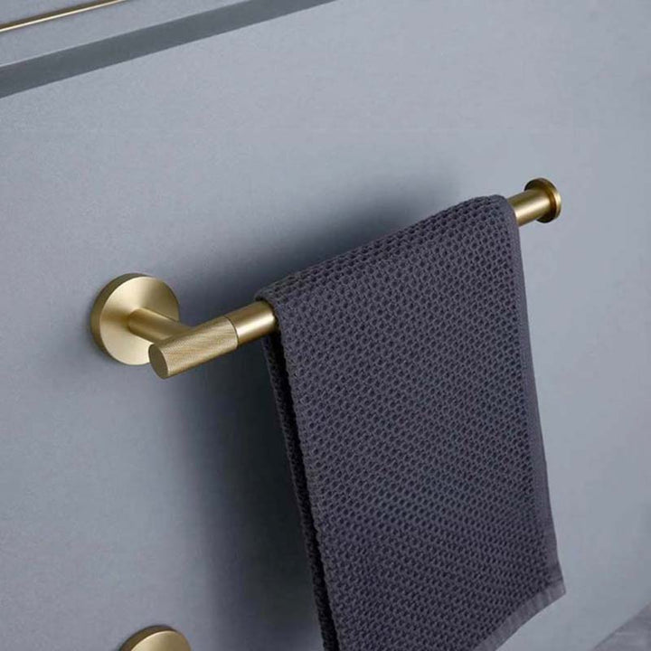 Gold towel rack with a gray towel on a light gray wall