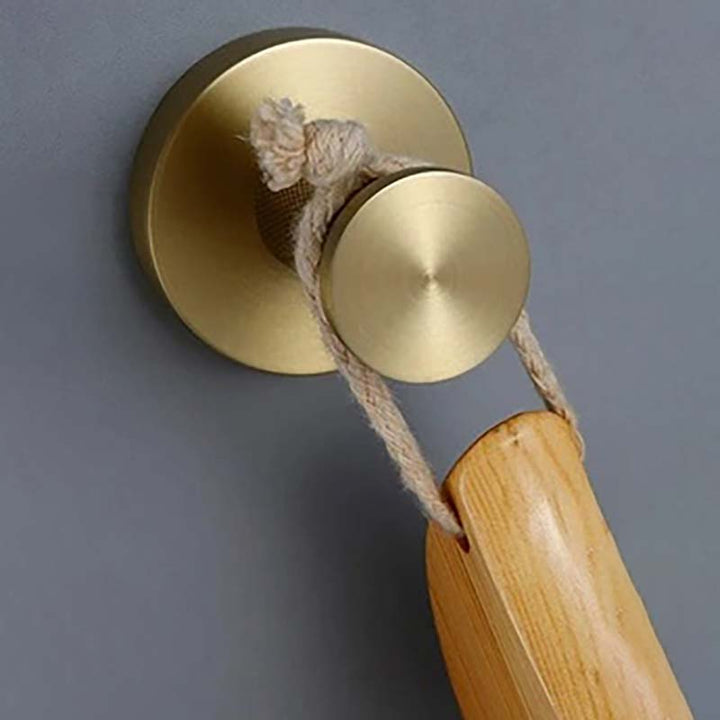 Brass wall hook with wooden handle on a gray background
