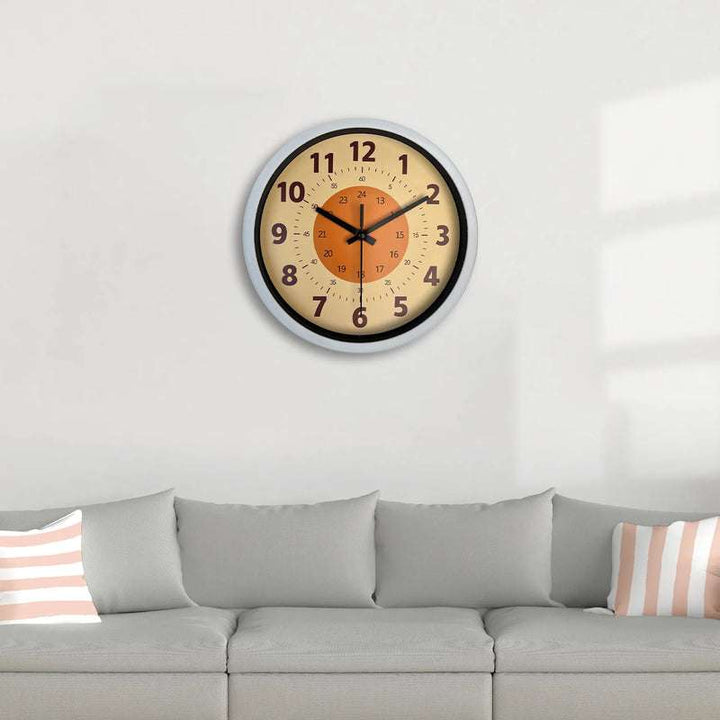Minimalist wall clock with orange center displayed above grey sofa in living room