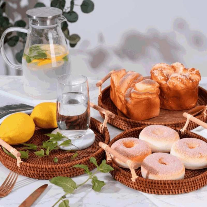 Set of natural wicker rattan trays with donuts, bread and fruit for stylish Scandinavian home entertaining