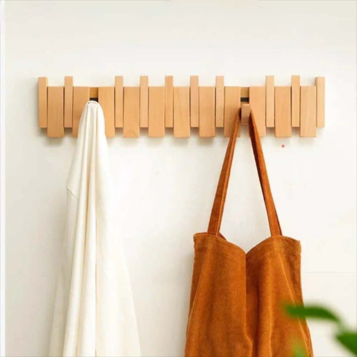 Wooden wall hook with a white towel and brown bag on a light background