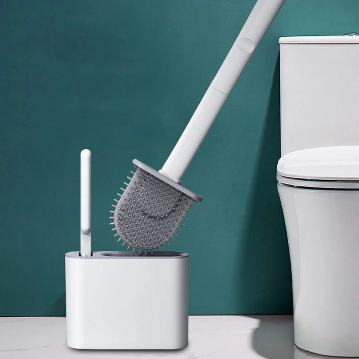 Toilet brush with holder next to a toilet against a teal wall