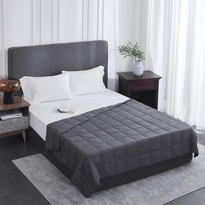 Bed with grey weighted blanket and pillows in a bedroom setting
