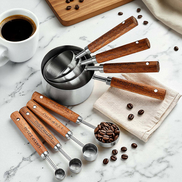Set of wooden-handled coffee measuring spoons on a marble surface with coffee beans and a cup.