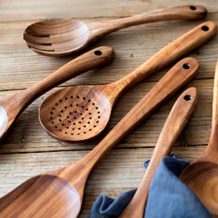 Close-up of solid teak cooking spoons on rustic wooden table, handmade utensils with natural grain