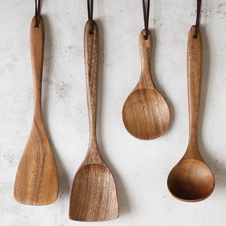 Set of four wooden spoons hanging against a light gray background