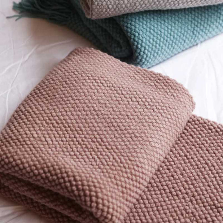 Folded acrylic waffle-knit blankets in muted pink, teal and grey tones for modern minimalist interior styling