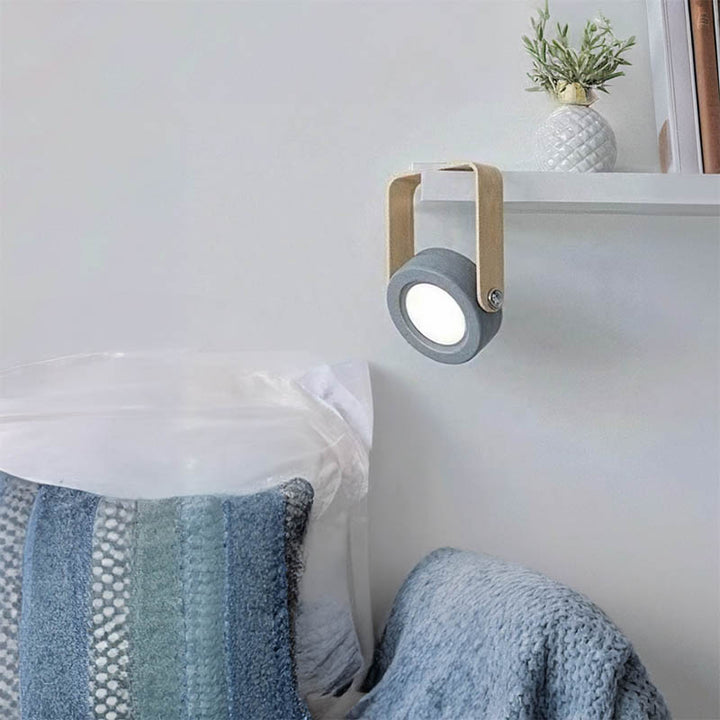 LYKT foldable LED lamp mounted on wall beside bed, ideal for reading light or nighttime ambiance.