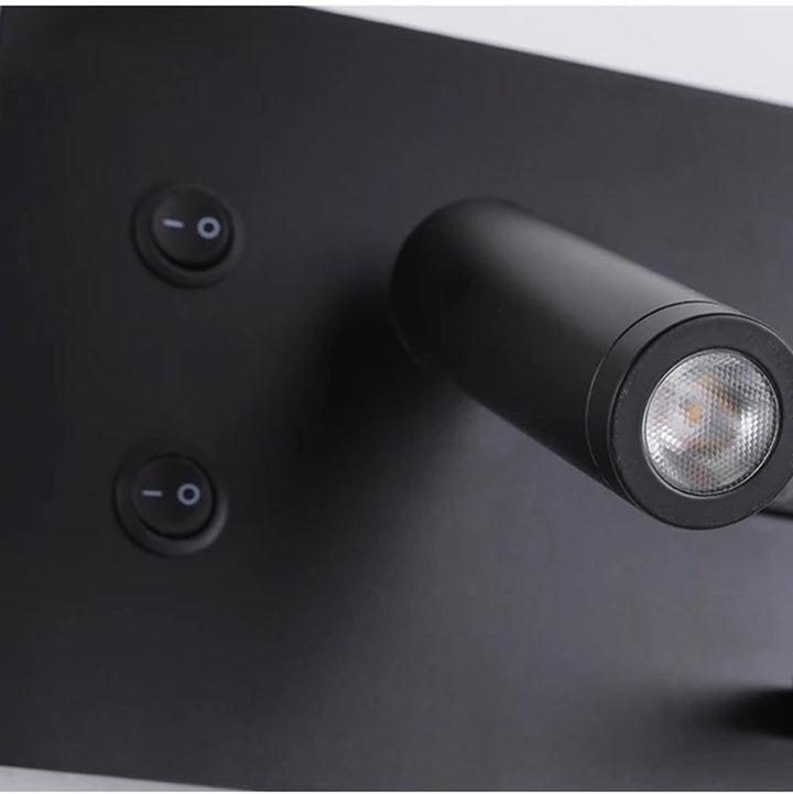 Black wall light fixture with two switches on a dark surface