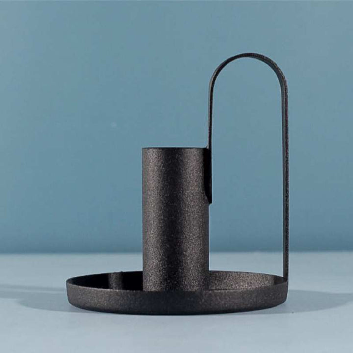 Minimalist black candle holder with round tray base and curved handle in matte finish