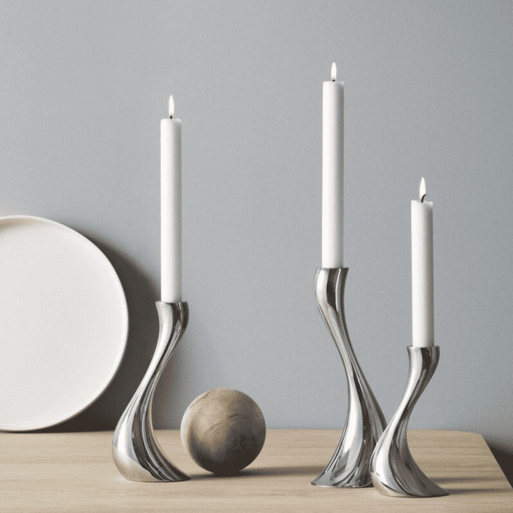 Three ceramic taper candle holders in varied heights styled on wooden table with decor