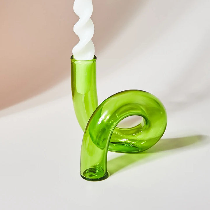 Vibrant green glass curved candle holder with white spiral taper candle in Scandinavian minimalist setting
