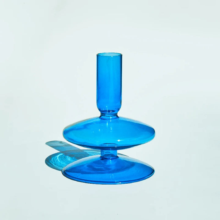 Bright sky-blue glass candle holder with smooth double-ring base reflecting soft natural light