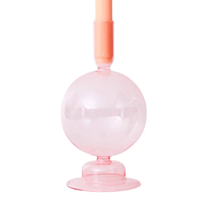 Pale pink glass round candle holder with peach taper candle in modern Scandinavian style