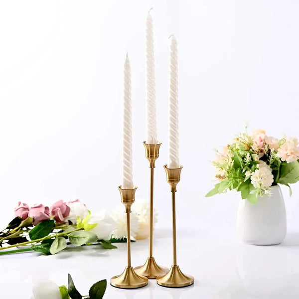 Gold metal taper holders with white candles, floral centrepiece dining décor