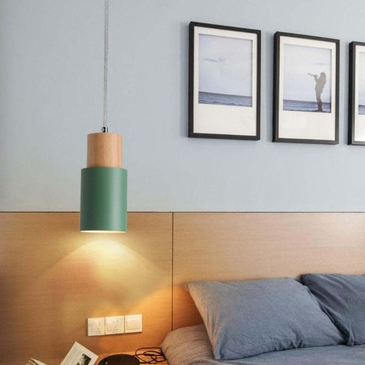 Green pendant light hanging above a bedside table in a cozy Scandinavian-style bedroom.