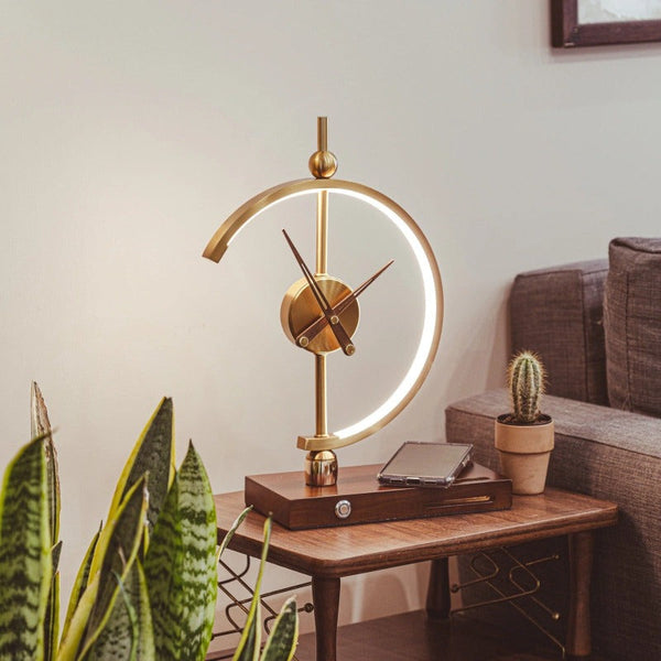 Gold LED lamp clock on wooden base with wireless charging, styled in a living room corner.
