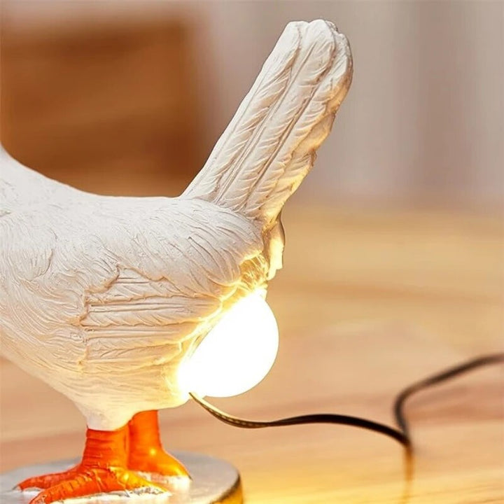 Close-up of chicken table lamp showing illuminated bulb and feather texture detail