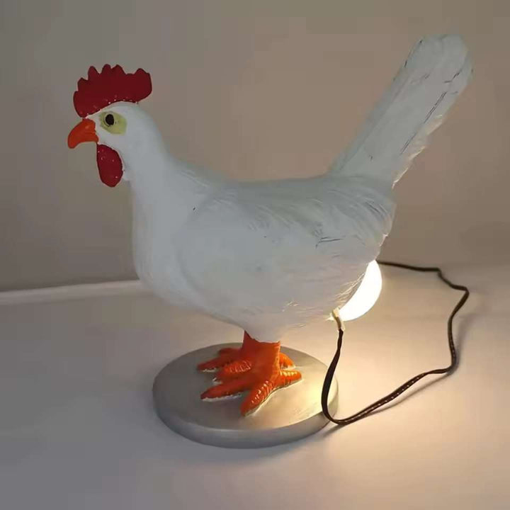 Chicken-shaped table lamp with glowing bulb and visible cord placed on neutral background