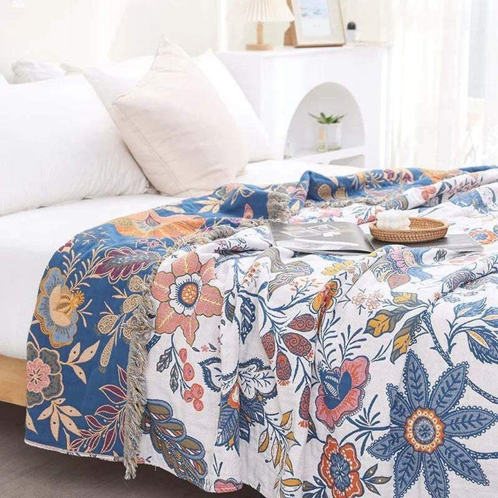 Lightweight cotton floral blanket in blue and white tones draped across a bright bedroom setup.