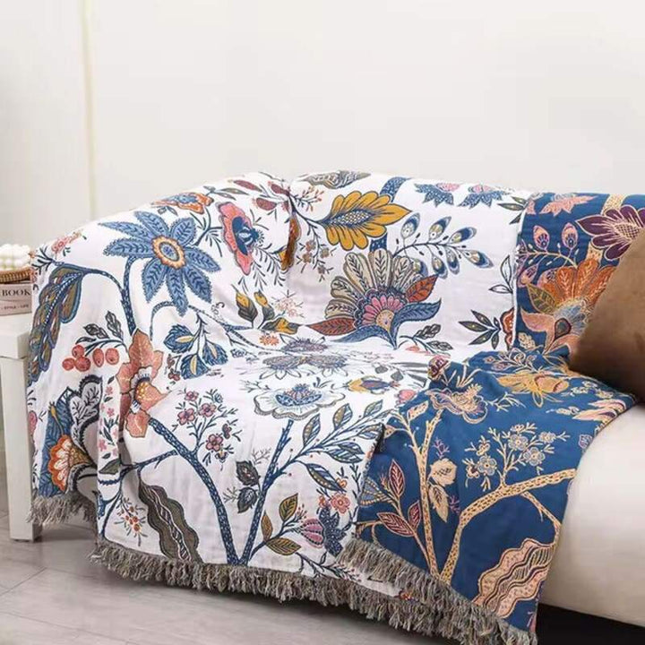Reversible blue and white floral cotton blanket styled over a sofa for cosy home décor.