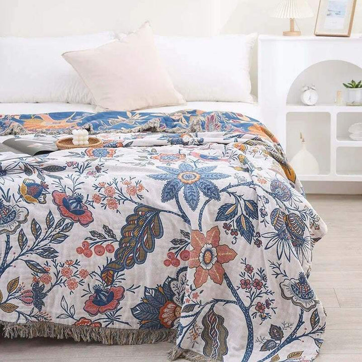 Cotton floral blanket styled neatly across a bed, showing multicoloured botanical design.