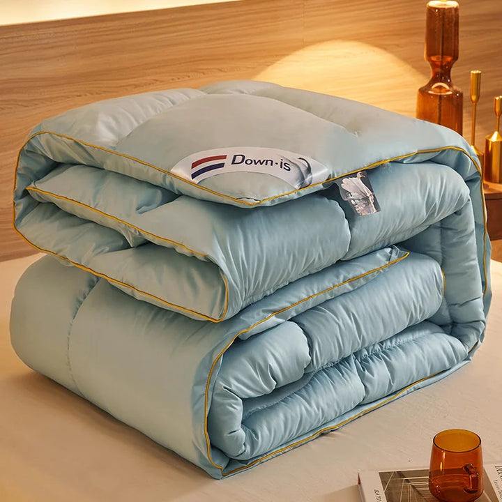 Light blue goose down comforter neatly folded on a bed with soft quilted padding and yellow piping.