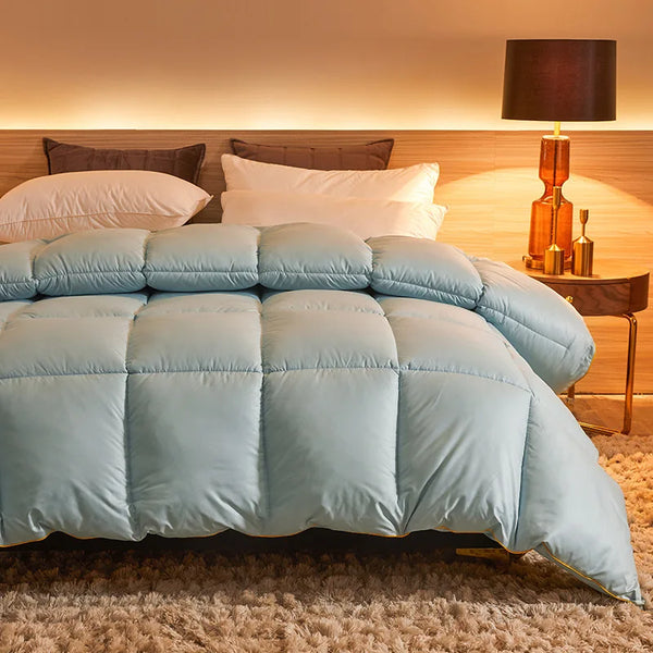 Light blue goose down comforter laid on a bed, showing thick quilted design and hotel-style coziness.