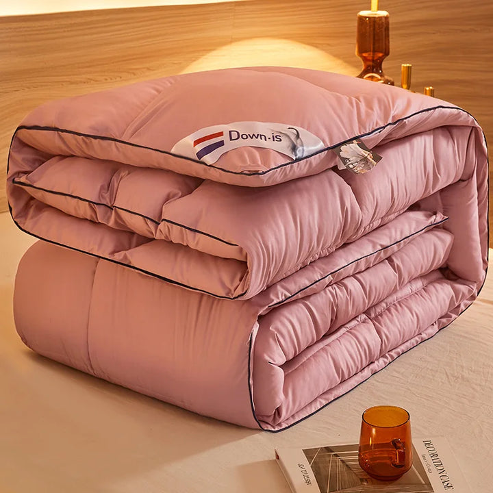 Pink goose down comforter folded neatly with quilted padding and contrasting dark edge piping.